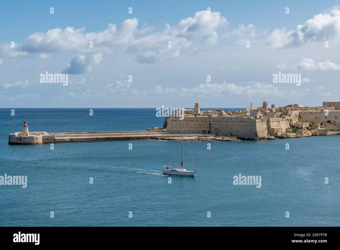 Una barca entra nella baia di la Valletta passando vicino alla Ricasoli East Breakwater, Kalkara, Malta Foto Stock