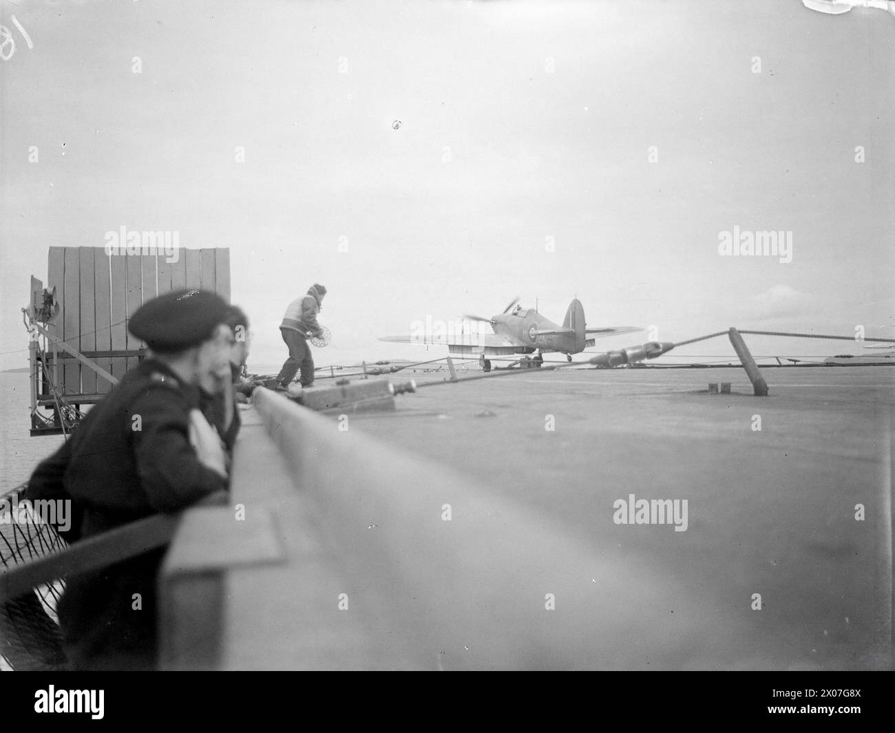I piloti della Fleet Air Arm si addestrano sugli sbarchi delle portaerei a bordo della HMS Argus al largo di Lamlash il 15–17 agosto 1943, con un caccia Hawker Hurricane che atterra durante il 25 ° anniversario della nave. Foto Stock