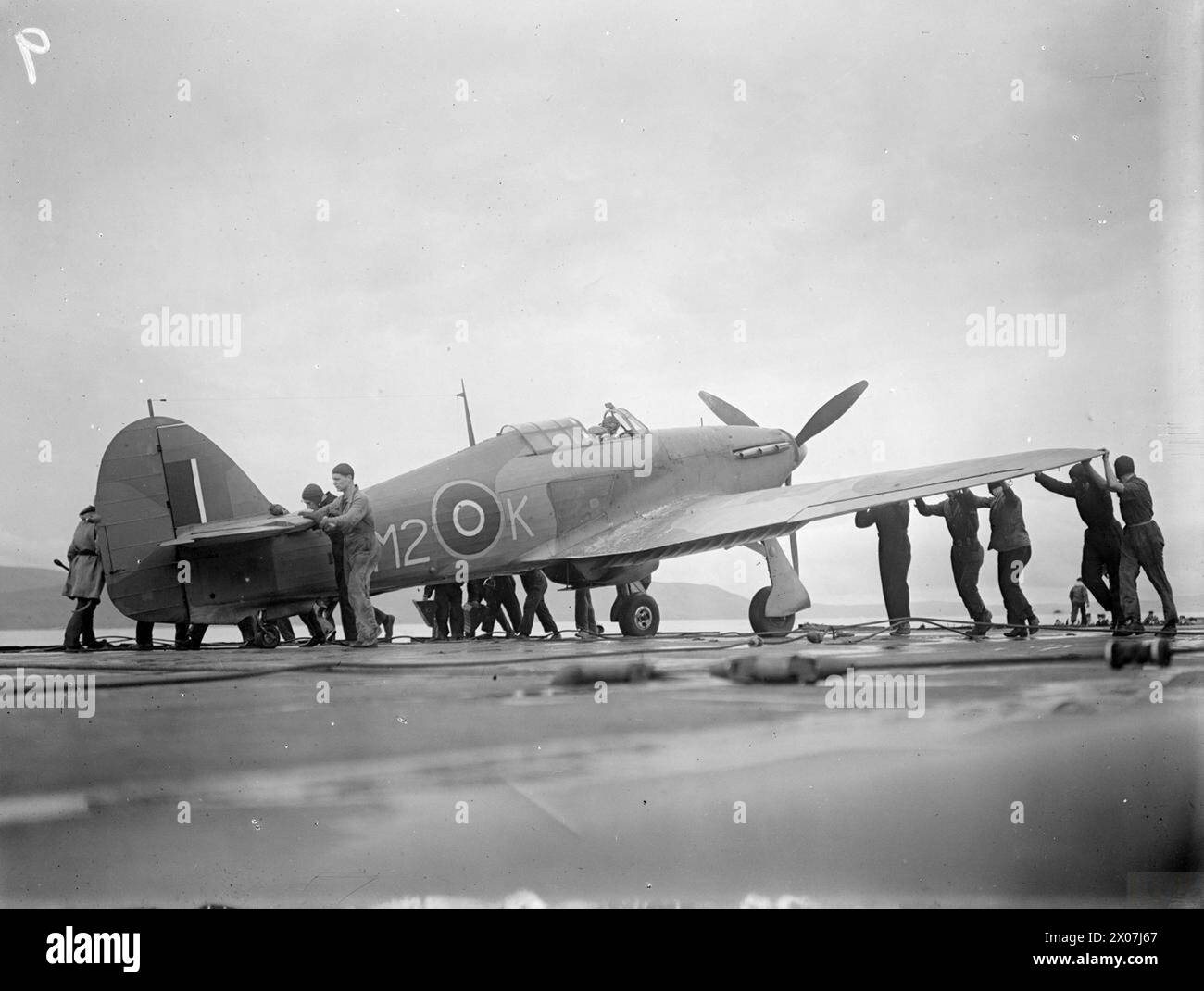 A bordo della HMS Argus al largo di Lamlash, dal 15 al 17 agosto 1943, una squadra della Fleet Air Arm respinge un Hawker Hurricane dopo l'atterraggio, mentre la portaerei celebra 25 anni di servizio e addestra i piloti nelle operazioni di portaerei. Foto Stock