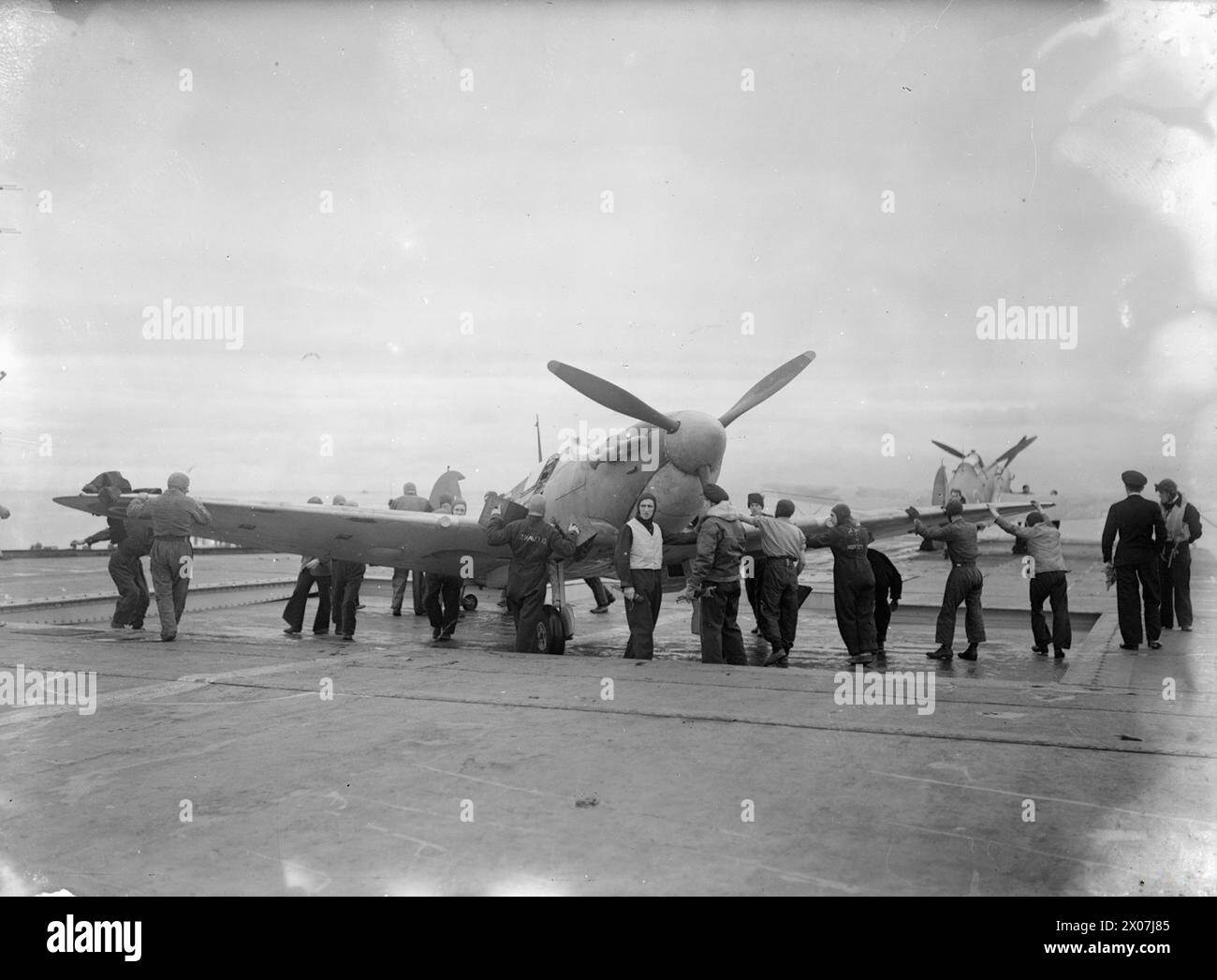 Il 15–17 agosto 1943, la HMS Argus al largo di Lamlash condusse un addestramento per piloti Fleet Air Arm, celebrando 25 anni di servizio, con un Supermarine Spitfire visto sull'hangar lift. Foto Stock