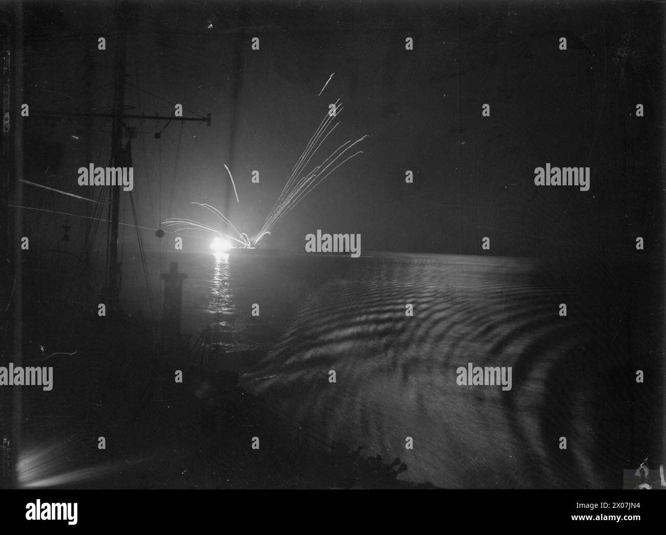 SALERNO; LA FLOTTA COMBATTE UN ATTACCO AEREO NOTTURNO. A BORDO DELLA HMS WARSPITE NELLA NOTTE DEL 8/9 SETTEMBRE 1943, QUANDO LE UNITÀ DELLA FLOTTA MEDITERRANEA CHE SOSTENEVA LE OPERAZIONI TERRESTRI IN ITALIA STAVANO COMBATTENDO UN ATTACCO DI BOMBARDAMENTI SILURO A BASSO LIVELLO NELLA BAIA DI SALERNO. DURÒ DUE ORE E IL DESTROYER INGLEFIELD ABBATTÉ UNO DEI RAIDERS. LA HMS WARSPITE SCHIVÒ CON SUCCESSO DUE SILURI. - Il fuoco anti-aereo in fuga da una portaerei durante l'attacco notturno di siluri-bombardieri nella baia di Salerno. A est di lei si vede poco la HMS VALIANT. L'albero principale della HMS WARSPITE appare in primo piano Foto Stock