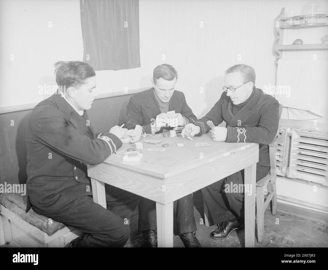 I primi e i secondi compagni e il principale operatore wireless giocano a poker a bordo della nave mercantile britannica Empire Kangaroo mentre sono in convoglio al largo della costa nord-orientale. Foto Stock