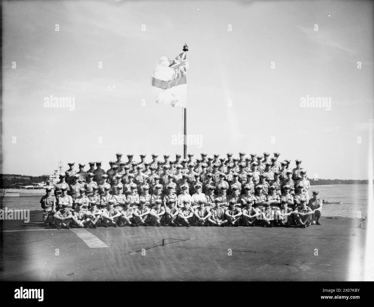 CON L'ILLUSTRE. FEBBRAIO 1945, A BORDO DELLA PORTAEREI HMS ILLUSTRIOUS NELLE ACQUE DELL'ESTREMO ORIENTE. - Il distaccamento dei Marine nell'ILLUSTRE. Fanno parte di questo gruppo il comandante della HMS ILLUSTRIOUS, comandante A Wallis, RN; capitano D C Mahoney, RM; Lieut B G Hartley, RM; Marine W Day, Ashberry, Swindon, che ha completato 22 anni di servizio, il caporale D Thomas, Perth, che ha vinto il DSM sulla HMS HARDY a Narvik, e il Marine R W A Dodge, di Bristol, che è al suo quarto anno di servizio sulla nave Foto Stock