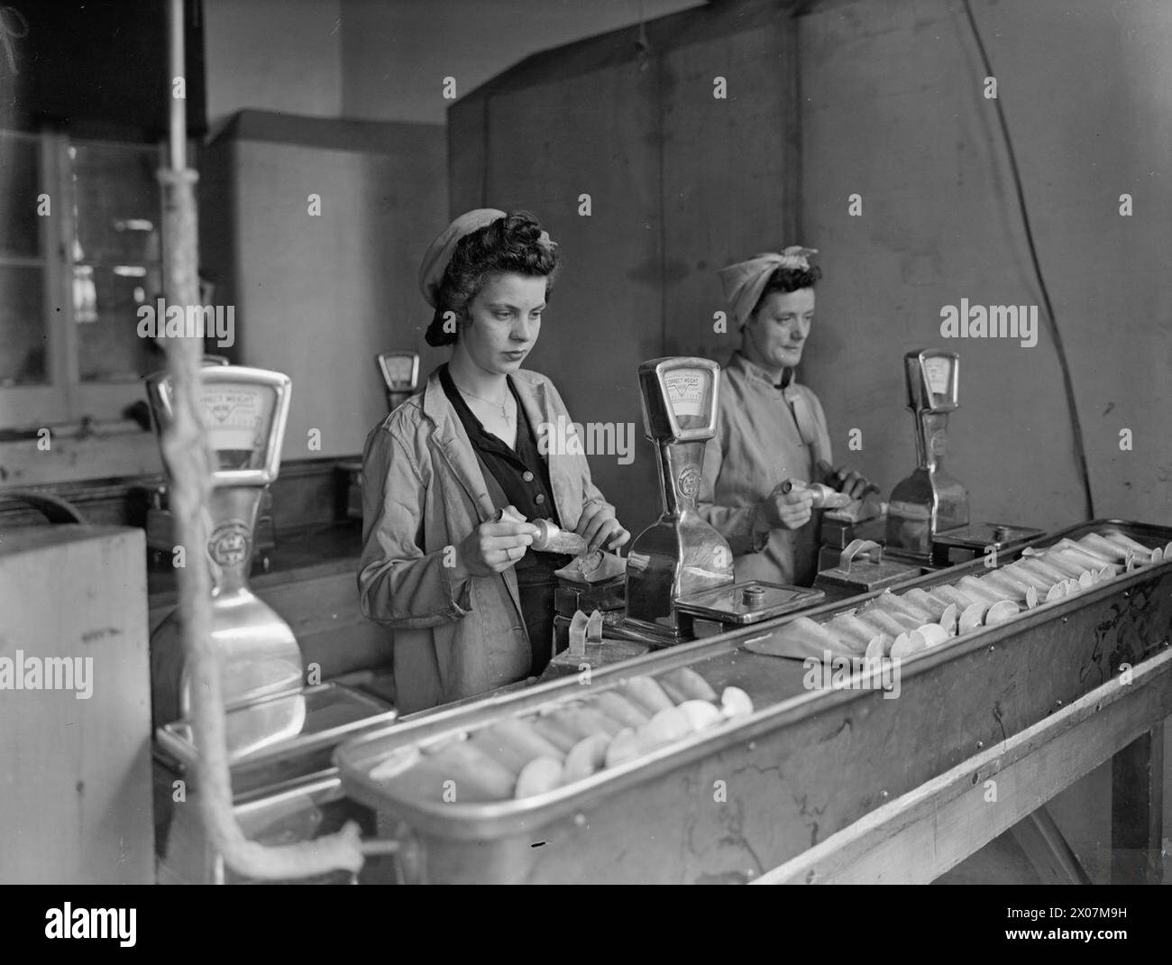 LIFE AT ROYAL NAVY ARMAMENT DEPOT PRIDDY'S HARD, GOSPORT, 25-30 LUGLIO 1944 - presso RNAD Priddy's Hard, Gosport, Gladys Mingay, 19 anni, e Gladys Cox, età 39 anni, con un esplosivo RDX per il riempimento di conchiglie navali da due libbre della Royal Navy Foto Stock