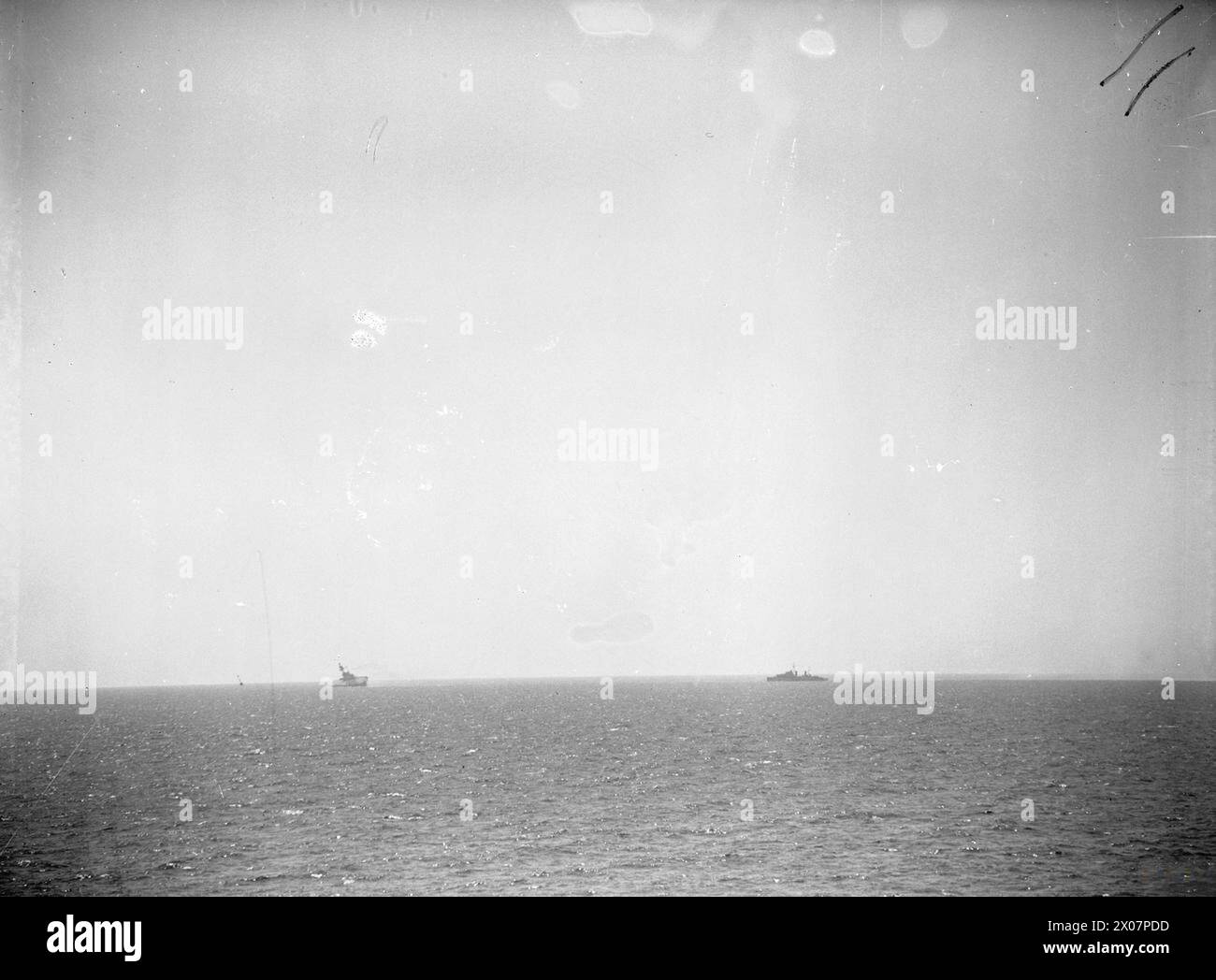 AFFONDAMENTO DELLA HMS EAGLE, MALTA, 11 AGOSTO 1942 - all'orizzonte la HMS EAGLE, portaerei classe Audacious, si sta quotando pesantemente a dritta. È in procinto di capalizzare e affondare nel Mar Mediterraneo, al largo di Malta, 11 agosto 1942. Un Dido Class Cruiser si sta dirigendo verso EAGLE per salvare i sopravvissuti della Royal Navy, EAGLE (HMS) Foto Stock