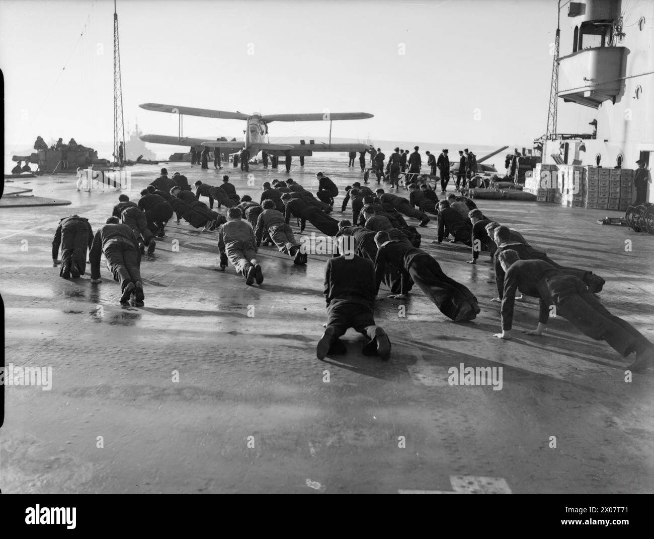 A Scapa Flow, i marinai eseguirono un addestramento fisico sul ponte di volo della portaerei HMS Victorious, con un Fairey Albacore del 820 Naval Air Squadron visibile all'estremità Foto Stock