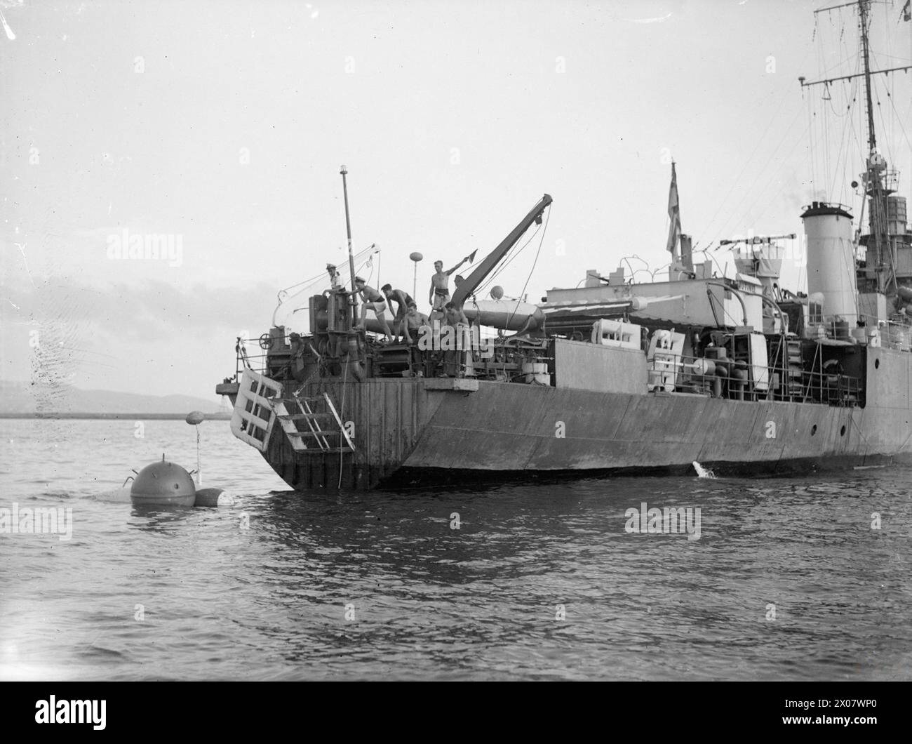 RENDERE I MARI DI NUOVO SICURI. AGOSTO 1945, IN MARE NEL GOLFO DI GENOVA. CON LA DODICESIMA FLOTTIGLIA DI DRAGAGGIO, OPERANTE NEL GOLFO DI GENOVA SOTTO IL COMANDO DEL COMANDANTE C SIMPSON, DSC, RN, COMANDANTE DI DRAGAGGIO DELL'ITALIA OCCIDENTALE. LAVORANO DALLE CARTE NEMICHE CONSEGNATE E SONO AIUTATI DAI SUPERMARINE WALRUS AIRCRAFT E DAL DISTACCAMENTO DI AVVISTAMENTO MINE BLIMP DELLA MARINA DEGLI STATI UNITI. - Le altre imbarcazioni si mantengono libere, in quanto una miniera è attirata nelle vicinanze dalla miniera MUTINE Royal Navy, HMS Mutine, Sloop, (1900) Foto Stock