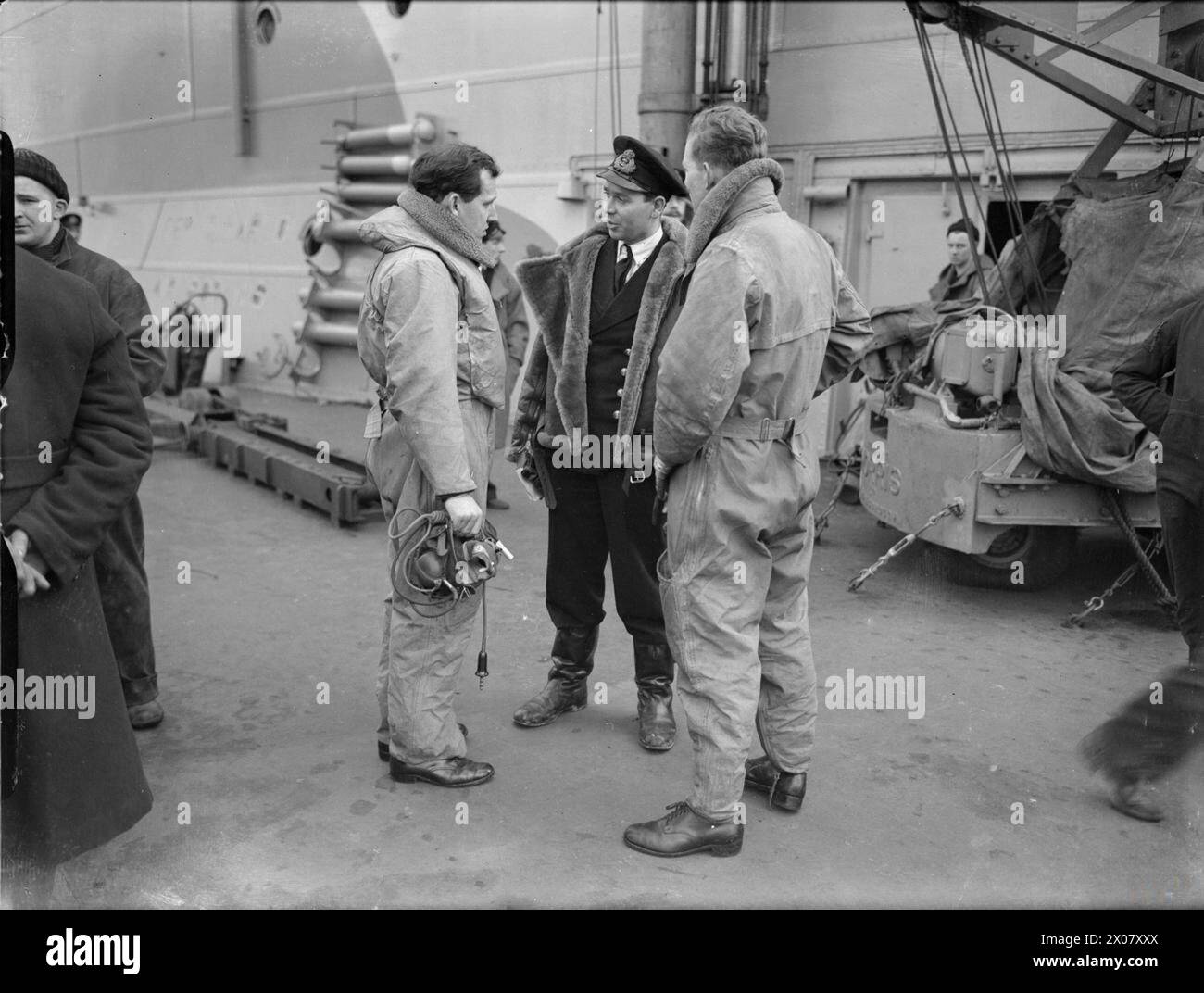 LA ROYAL NAVY DURANTE LA SECONDA GUERRA MONDIALE - il tenente J C N Shrubsole, RN (con cappello), parla con il tenente comandante Plugge, RN, in kit di volo, comandante del 832 Squadron, Fleet Air Arm a bordo della HMS VICTORIOUS. Nota la gru a ponte dietro il trio Royal Navy, VICTORIOUS (HMS), portaerei, Royal Navy, Fleet Air Arm, Naval Air Sqdn, 833 Foto Stock