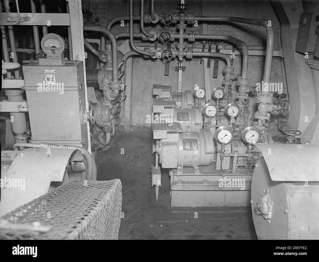 NELLA PORTAEREI BRITANNICA HMS INDEFATIGABLE. 22 FEBBRAIO 1944, ROSYTH. - Nella stanza CO2. Sul lato destro sono visibili tre pompe di circolazione che forniscono acqua salata ai tre condensatori. Il lato sinistro è il motorino di avviamento del compressore NO2 ad azionamento elettrico Foto Stock