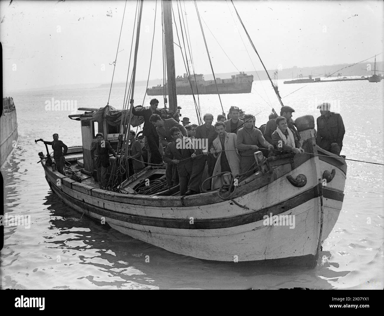 Una nave di salvataggio arriva a Termoli, in Italia, trasportando ex prigionieri di guerra salvati da dietro le linee nemiche. Una fanteria da sbarco è visibile sullo sfondo. Le fotografie documentano le operazioni di evacuazione e salvataggio navali durante la seconda guerra mondiale Foto Stock