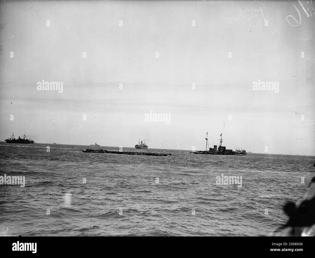 Dal 6 all'8 giugno, la HMS Aristocrat trasportò personale attraverso il Canale della Manica ad Arromanches per lo sbarco del porto prefabbricato di Mulberry e del gruppo associato. Una sezione di un traghetto Rhino è visibile al largo di Arromanches. Foto Stock
