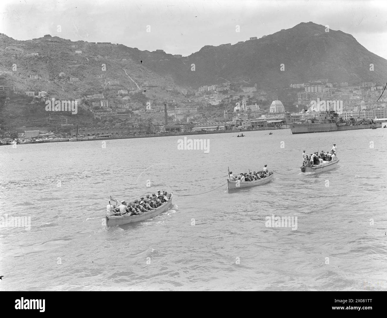 Le navi da sbarco della HMS Euryalus sbarcano per occupare i moli di Hong Kong il 30 agosto 1945. La HMS Kempemfelt, la prima nave della Task Force al comando del contrammiraglio C. H. J. Harcourt, entra nel porto di Victoria. La registrazione fotografica documenta la rioccupazione, le operazioni navali e lo spiegamento della flotta. Foto Stock