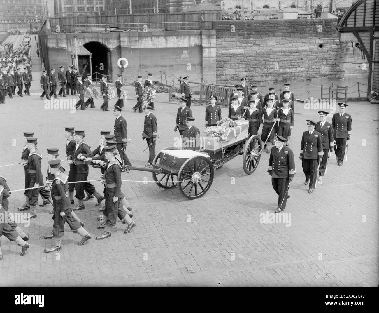 CAPITANO WALKER SEPOLTO IN MARE. 12 LUGLIO 1944, A LIVERPOOL BAY. DOPO IL SERVIZIO PRESSO LA CATTEDRALE DI LIVERPOOL, IL CORPO DEL CAPITANO F J WALKER, CB, DSO, RN, ACE U-BOAT FIGHTER, ERA IMPEGNATO SUL MARE ALL'INGRESSO DEL MERSEY. - Il corteo che arriva al Princes Landing Stage. L'ammiraglio Sir Max Horton, C in C Western si avvicina, cammina di fronte al gruppo della corona dietro i portatori di palle (tutti i colleghi del capitano Walker) Foto Stock