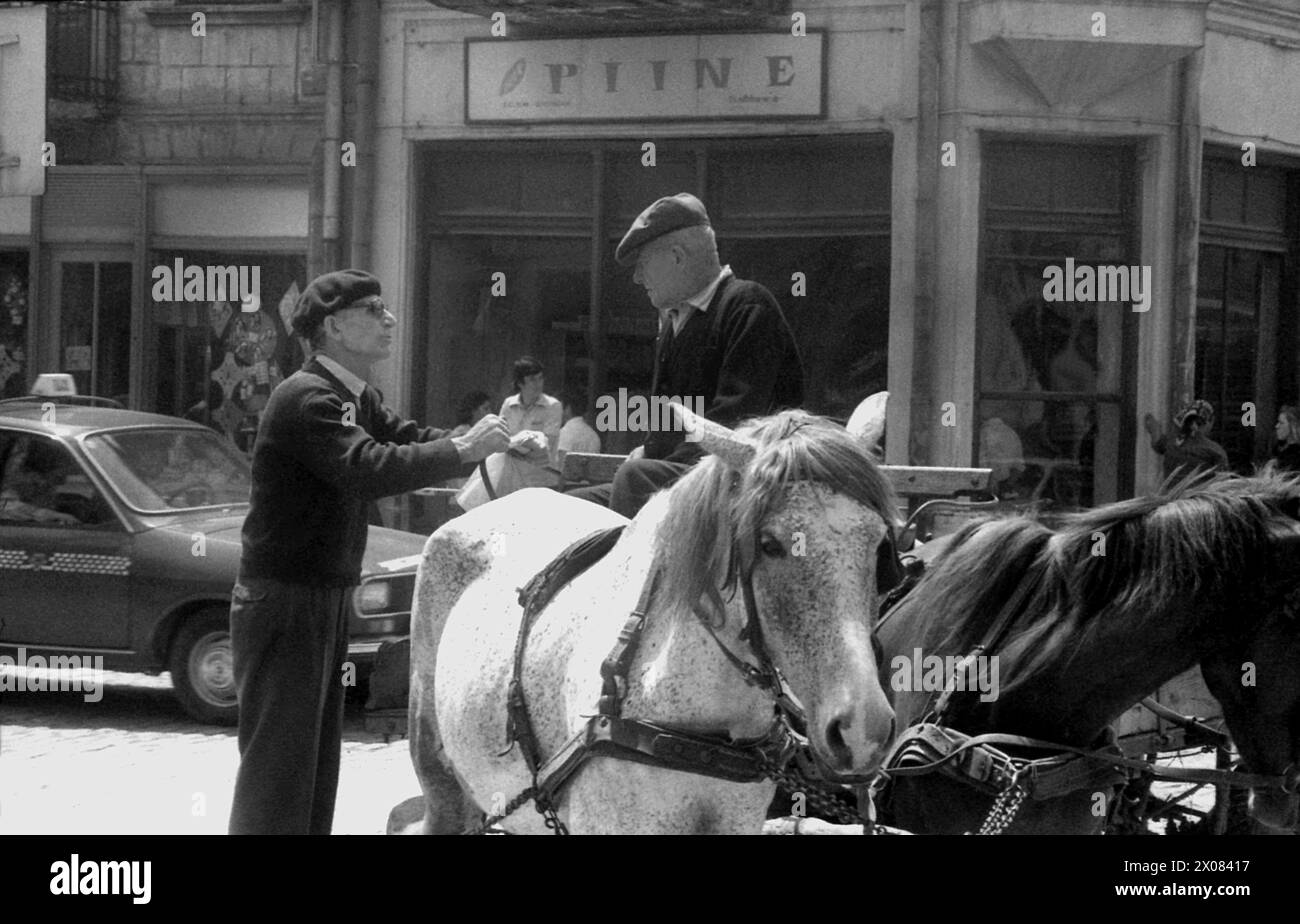 Repubblica Socialista di Romania negli anni '1970 Un uomo che cavalca un carro trainato da cavalli che parla con un altro sulla strada di una città di provincia. Foto Stock