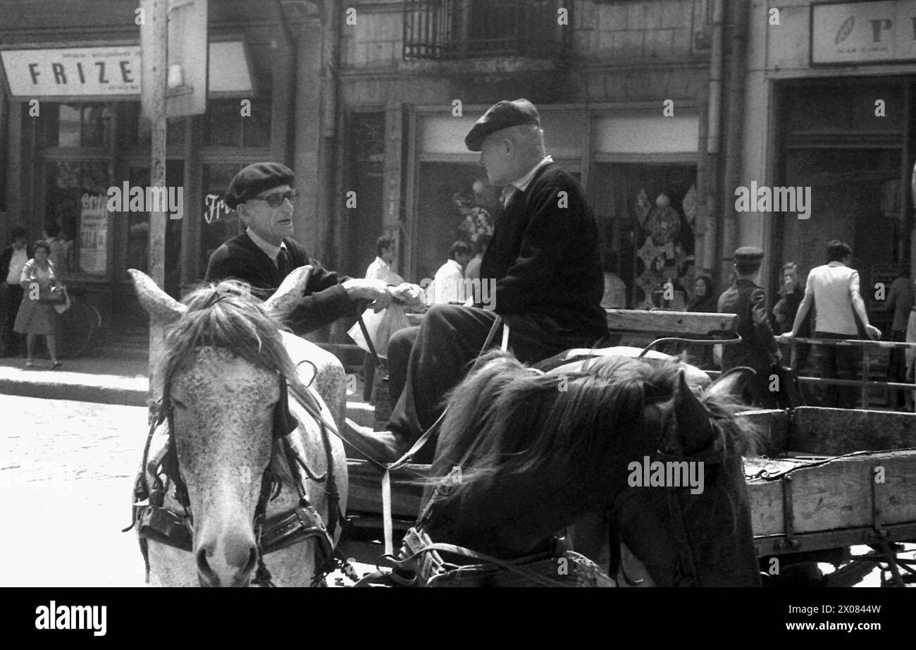Repubblica Socialista di Romania negli anni '1970 Un uomo che cavalca un carro trainato da cavalli che parla con un altro sulla strada di una città di provincia. Foto Stock