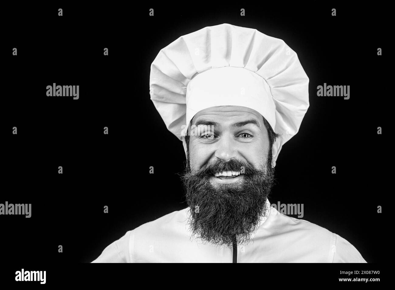 Uomo barbuto in uniforme da chef. Chef professionista felice. Chef, cuoco o fornaio maschile in cappello bianco e grembiule. Cucina, professione e affari. Divertente Foto Stock