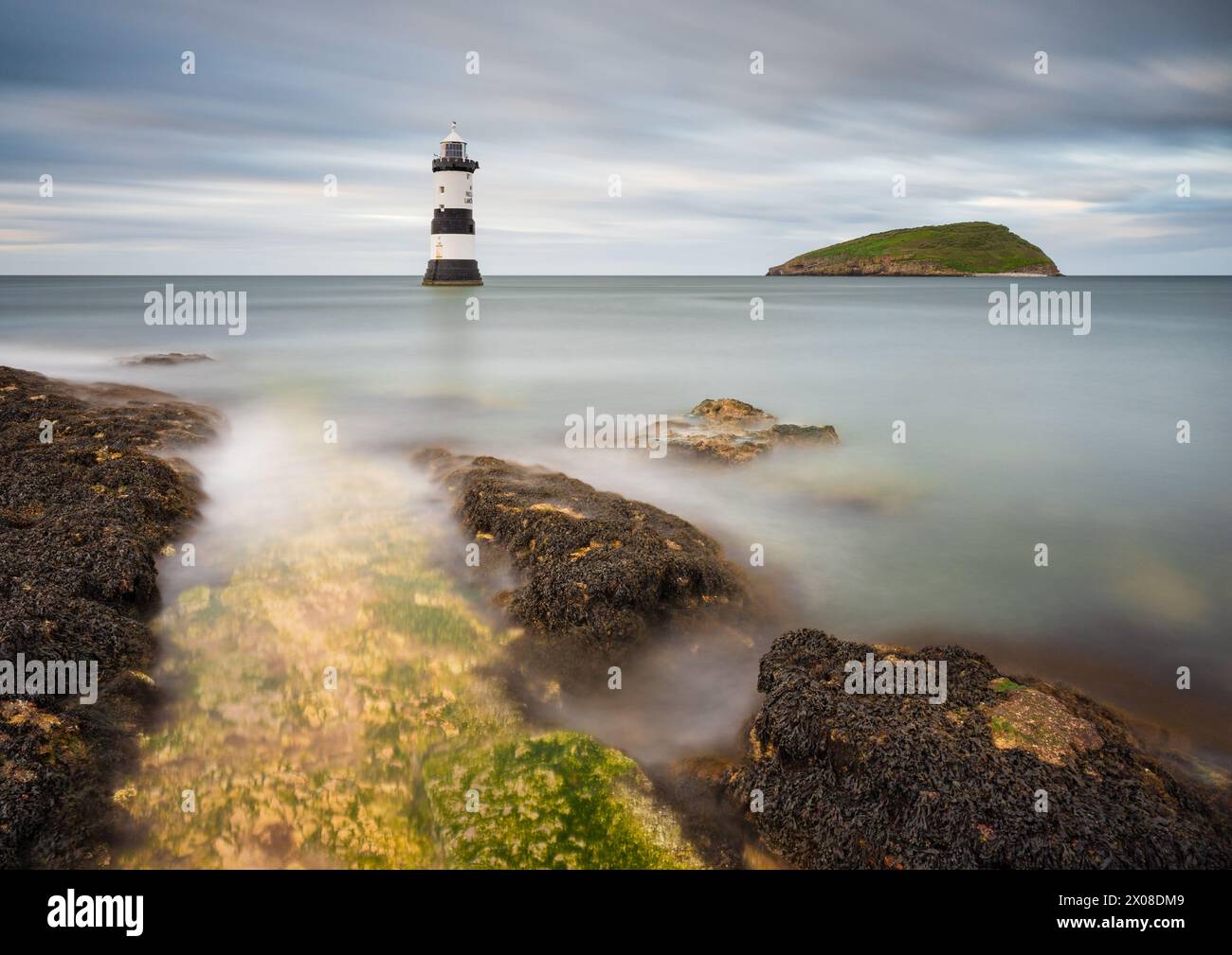 Il faro di Trwyn Du a Penmon Point in Anglesey è circondato da una marea crescente in un pomeriggio coperto mentre le nuvole scorrono nel cielo sopra. Foto Stock Il faro di Trwyn Du a Penmon Point in Anglesey è circondato da una marea crescente in un pomeriggio coperto mentre le nuvole scorrono nel cielo sopra. Foto Stock