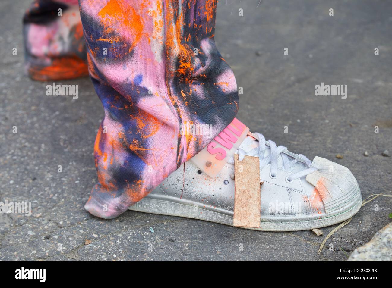 MILANO, ITALIA - 21 FEBBRAIO 2024: Uomo con Adidas Swlag sneakers e pantaloni con colori di vernice prima della sfilata di Fendi, Milano Fashion Week Street Foto Stock
