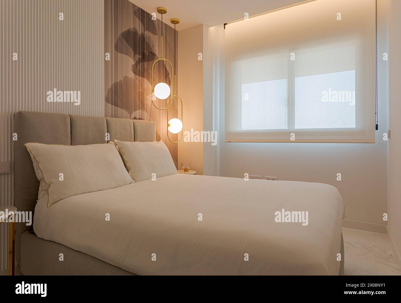 Camera dal design moderno con illuminazione elegante, comodo letto beige, carta da parati artistica e grande finestra con luce naturale Foto Stock