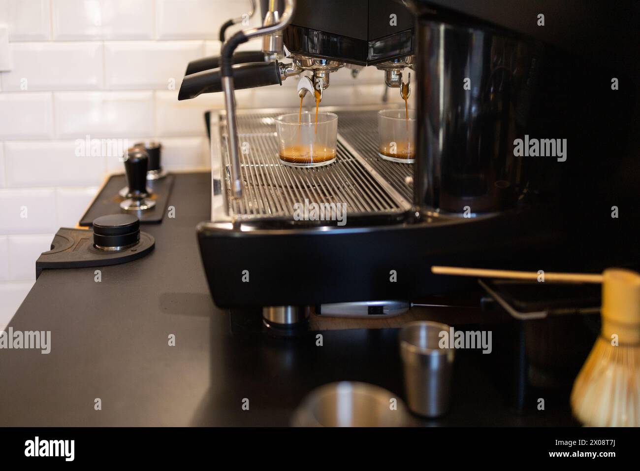 Immagine ravvicinata di una macchina da caffè che prepara caffè fresco, con un espresso ricco che scorre in due tazze chiare su un vassoio antigoccia Foto Stock