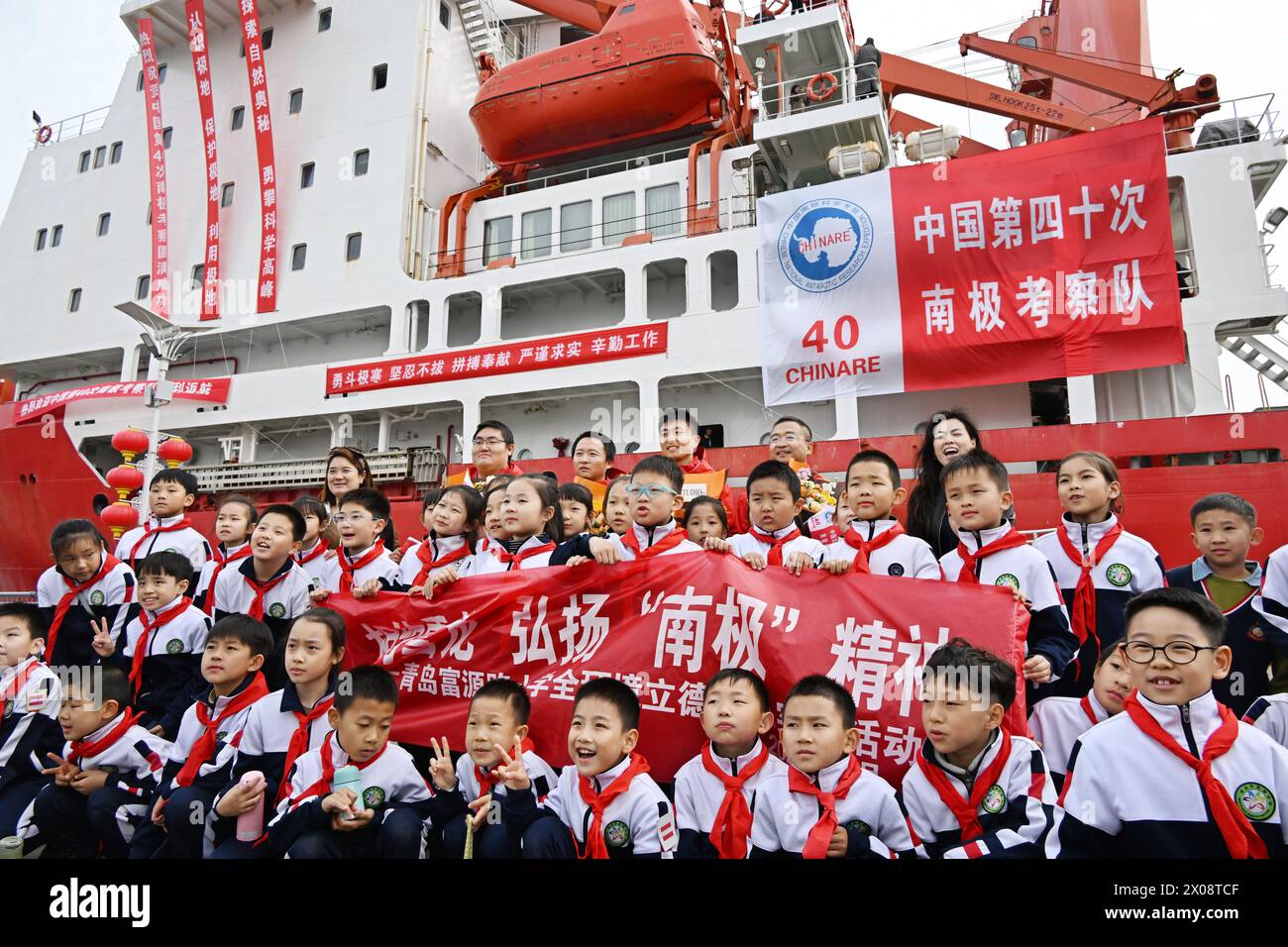 (240410) -- QINGDAO, 10 aprile 2024 (Xinhua) -- studenti e membri della squadra della spedizione posano per una foto di gruppo davanti al rompighiaccio Xuelong in un porto di Qingdao, nella provincia di Shandong della Cina orientale, 10 aprile 2024. Il rompighiaccio di ricerca cinese Xuelong mercoledì è arrivato in un porto di Qingdao dopo aver completato la sua ultima spedizione in Antartide e ospiterà un open House di tre giorni al pubblico.la 40a spedizione antartica della Cina è partita da Shanghai il 1 novembre, 2023 e completarono con successo varie missioni di spedizione che durarono 161 giorni per un totale di oltre 81.000 miglia nautiche. Foto Stock