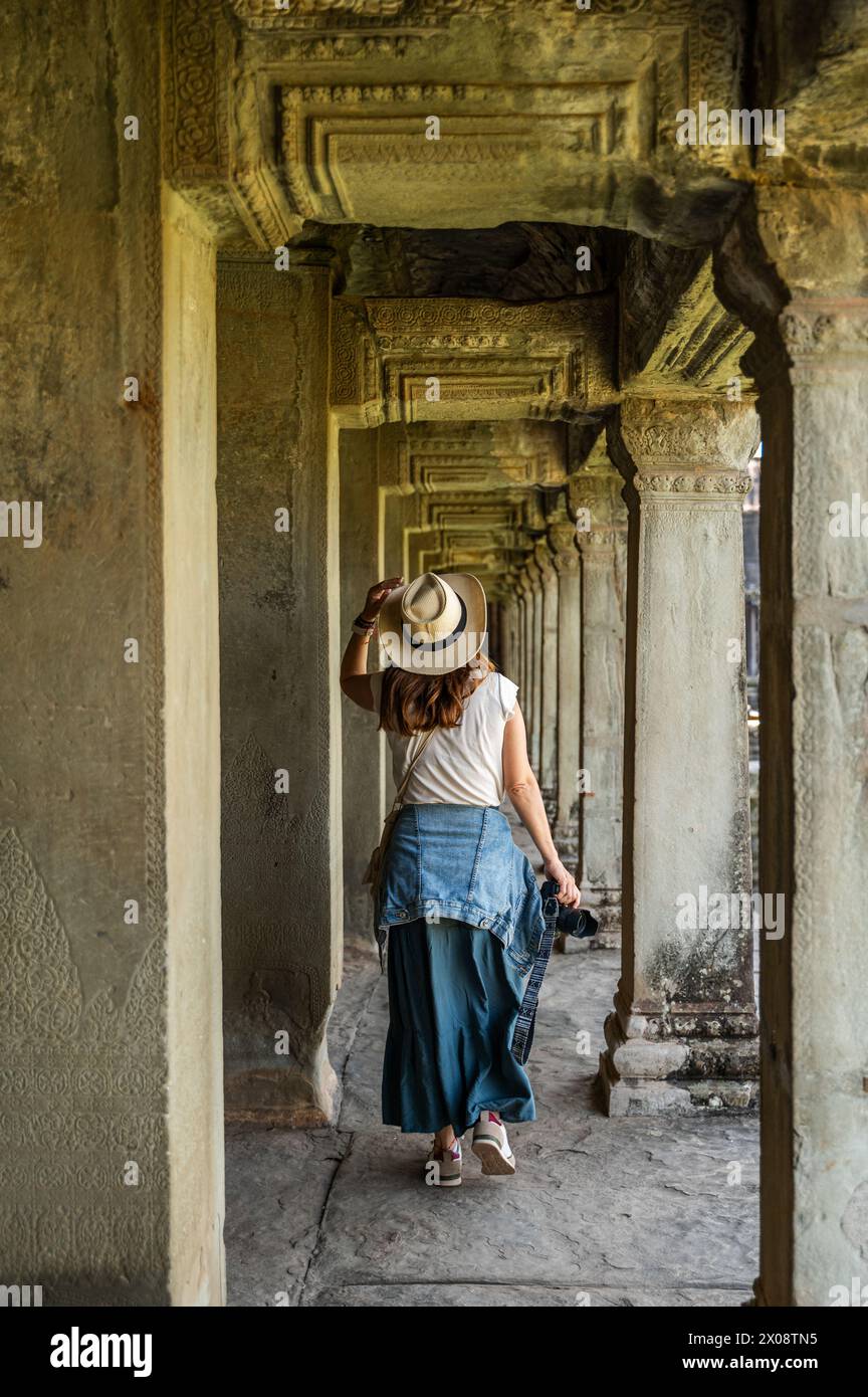 Un turista cattura la bellezza dei corridoi di Angkor Wat, rivelando l'intricata architettura dell'antico tempio. Foto Stock