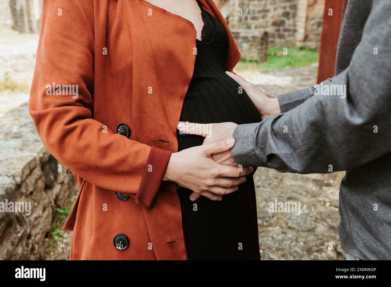 I genitori in attesa tengono le mani amorevolmente su una pancia incinta all'aperto Foto Stock