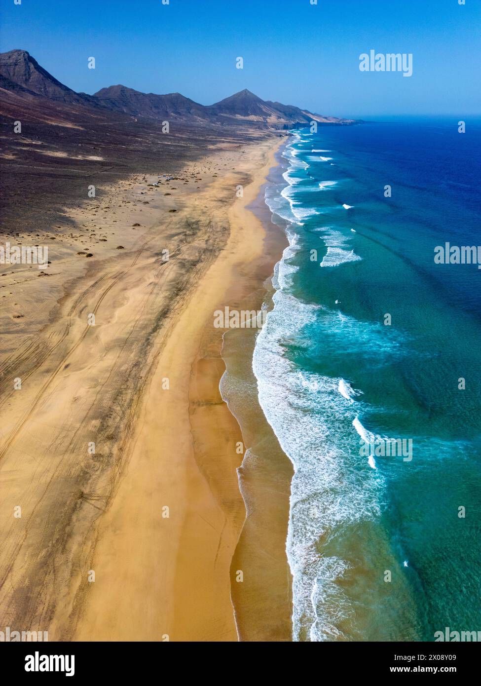Scatto aereo mozzafiato che cattura la vasta distesa sabbiosa della spiaggia di Cofete con acque turchesi incontaminate lungo la costa frastagliata di Fuerteventura, showcasi Foto Stock