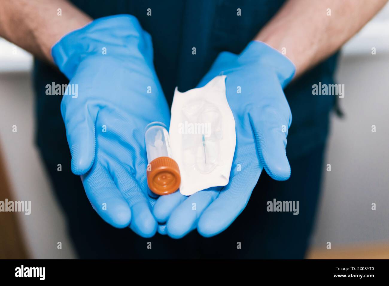 Primo piano di mani anonime con guanti che contengono una siringa medica sigillata e un flaconcino, pronti per la somministrazione sterile di farmaci Foto Stock