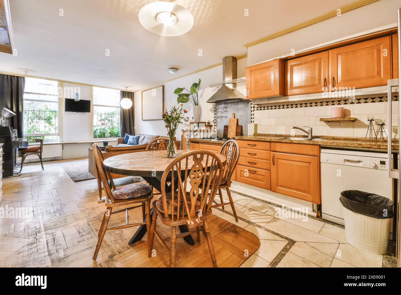 Una cucina moderna con armadi in legno, combinata con una comoda zona pranzo, caratterizzata da grandi finestre e un'ampia illuminazione. Foto Stock