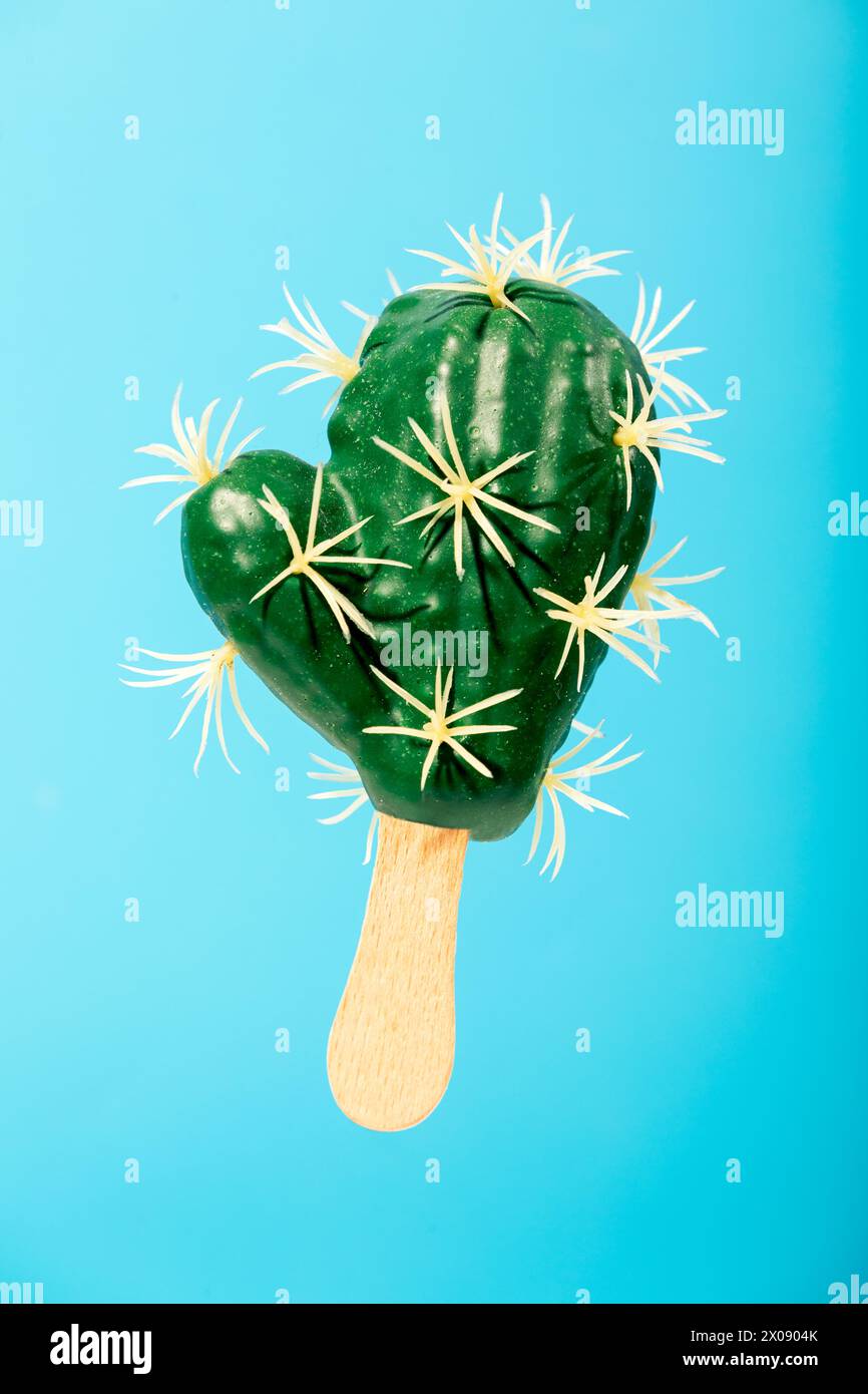 Un'immagine creativa con un pistoncino a forma di cactus con spine, disegnato su un bastoncino di legno su uno sfondo blu vibrante. Foto Stock