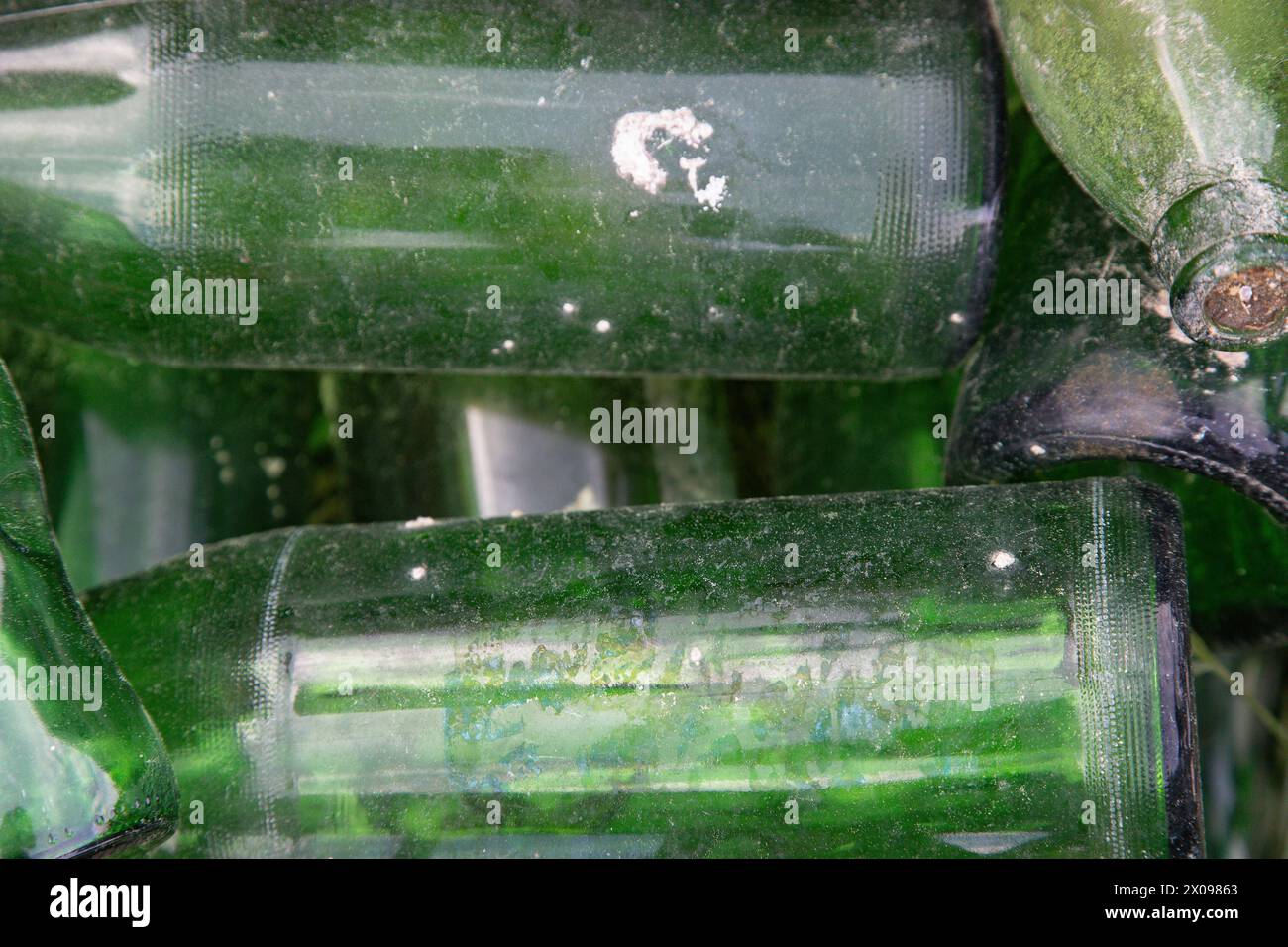 Primo piano di flaconi di vetro verde vuoti, usati e sporchi lasciati a caso. Background astratto, concetto di riciclo, riutilizzo, recupero. Foto Stock