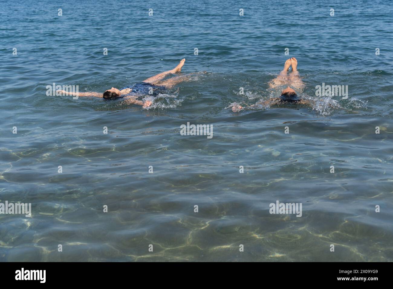 Due nuotatori che praticano il backstroke in acque cristalline dell'oceano. Foto Stock