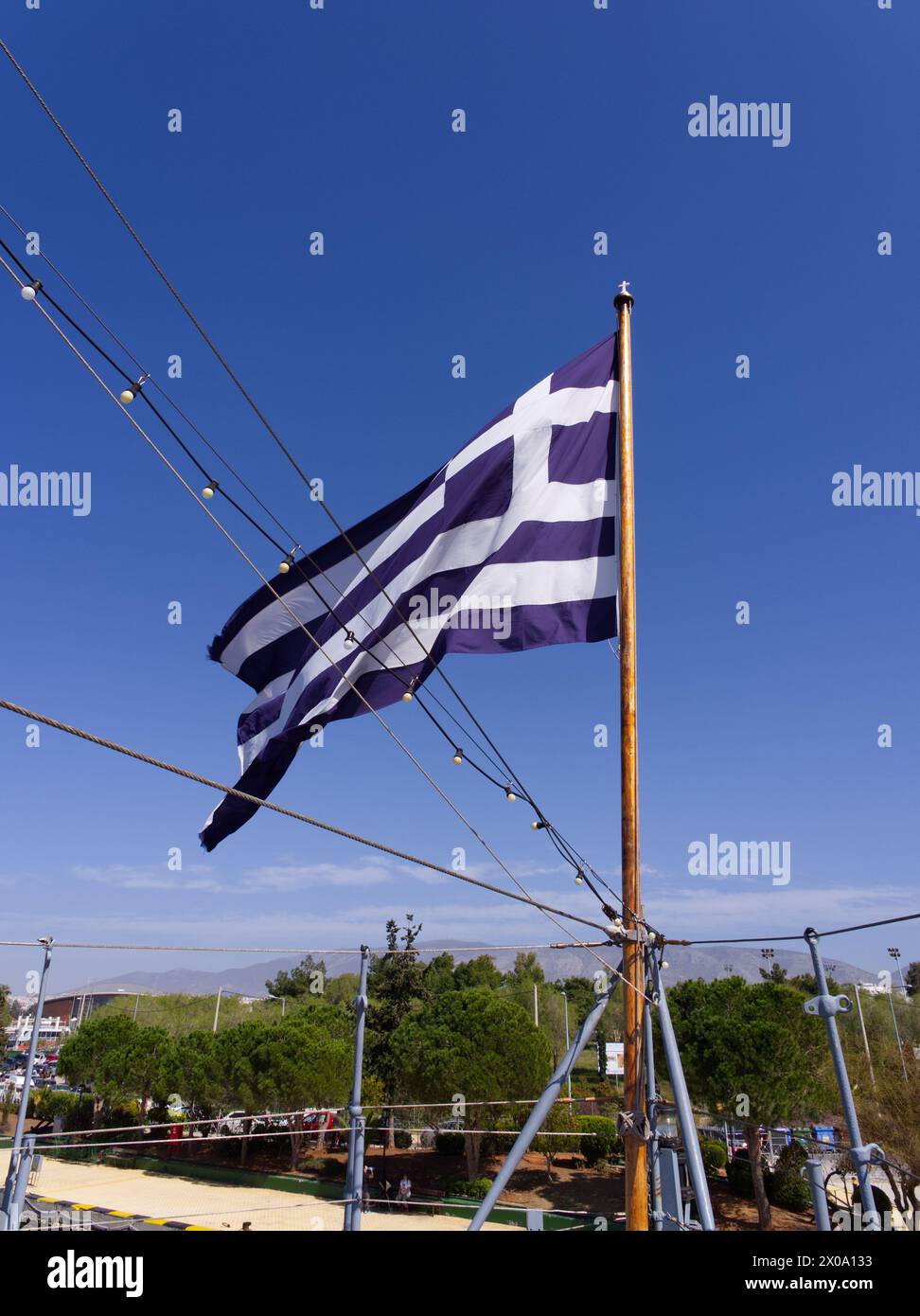Atene, Grecia - 31 marzo 2023: Bandiera greca sulla nave da battaglia Georgios Averof e museo ormeggiati a Flisvos Marina. Foto Stock
