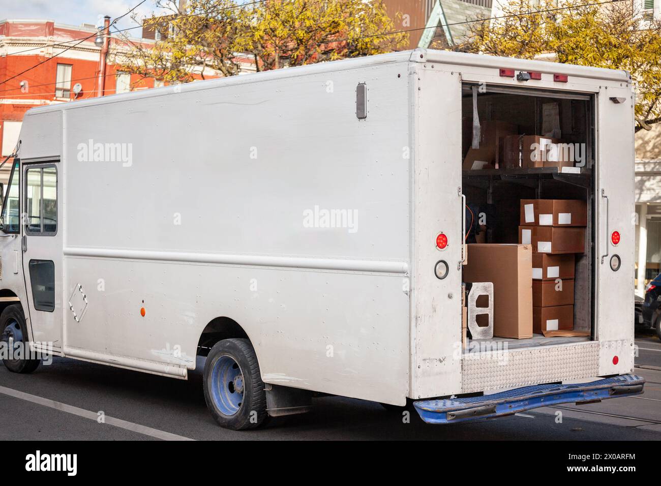 Scattata su una strada cittadina, questa immagine mostra un furgone bianco nordamericano con le sue porte posteriori aperte, che rivela una serie di pacchi pronti per la consegna Foto Stock