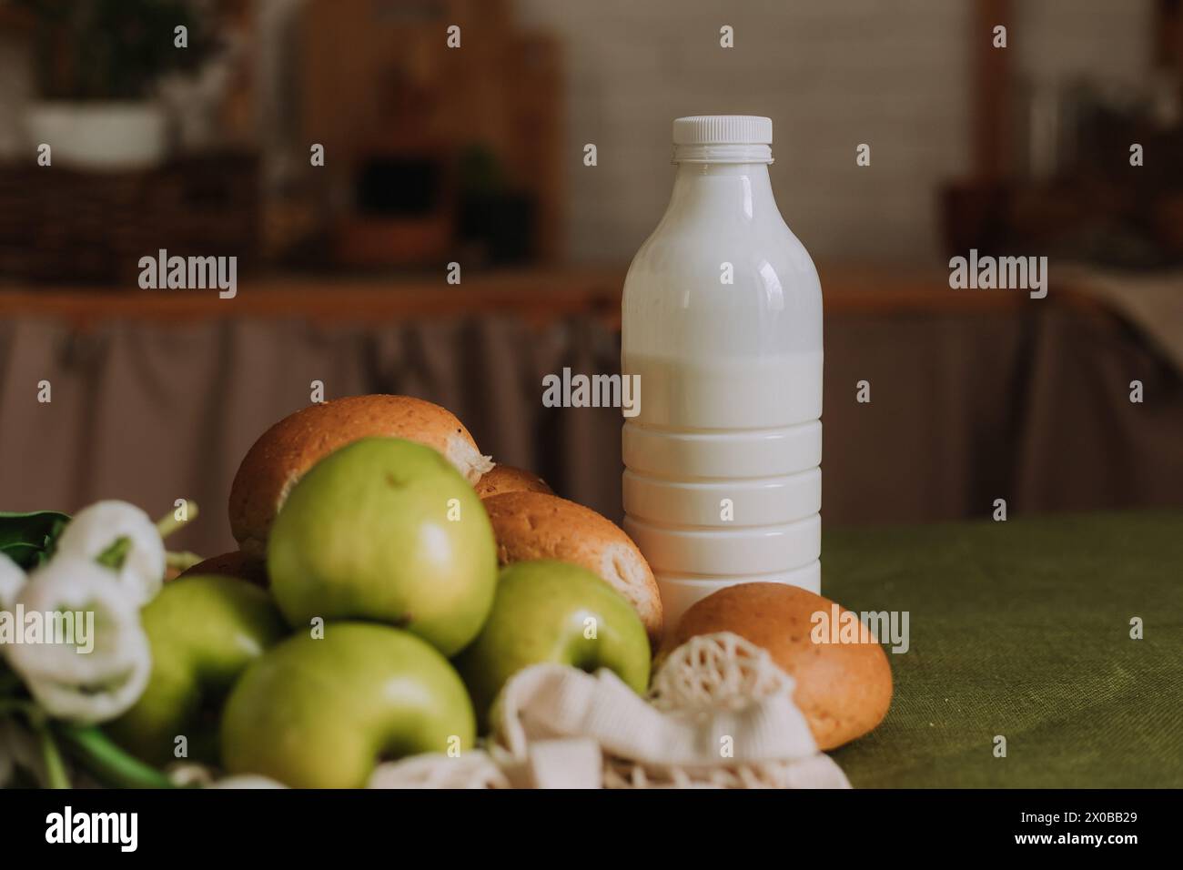 biberon con kefir, latte e mele verdi in una cucina di legno. Foto di alta qualità Foto Stock