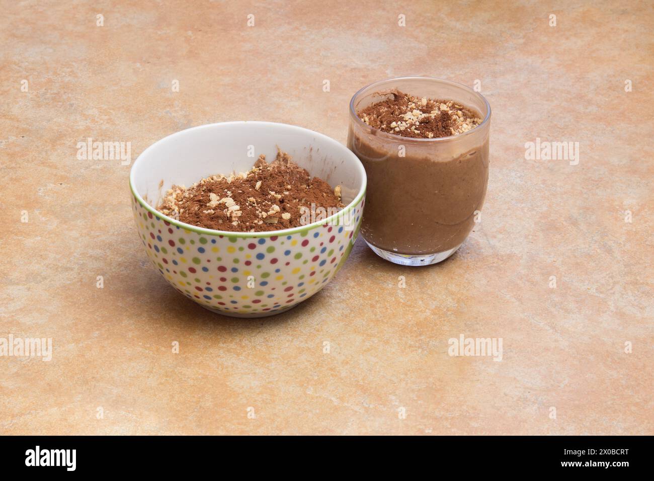 Una ciotola e un bicchiere riempiti con una crema di mousse al cioccolato fatta in casa adornata con noci tritate e spazio per copiare. Dessert cremoso. Foto Stock