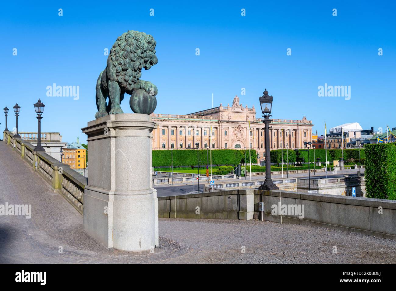 Una maestosa statua di leone con la camera del Parlamento a Stoccolma, Svezia, simboleggia la tutela e la storia contro un cielo azzurro. Foto Stock