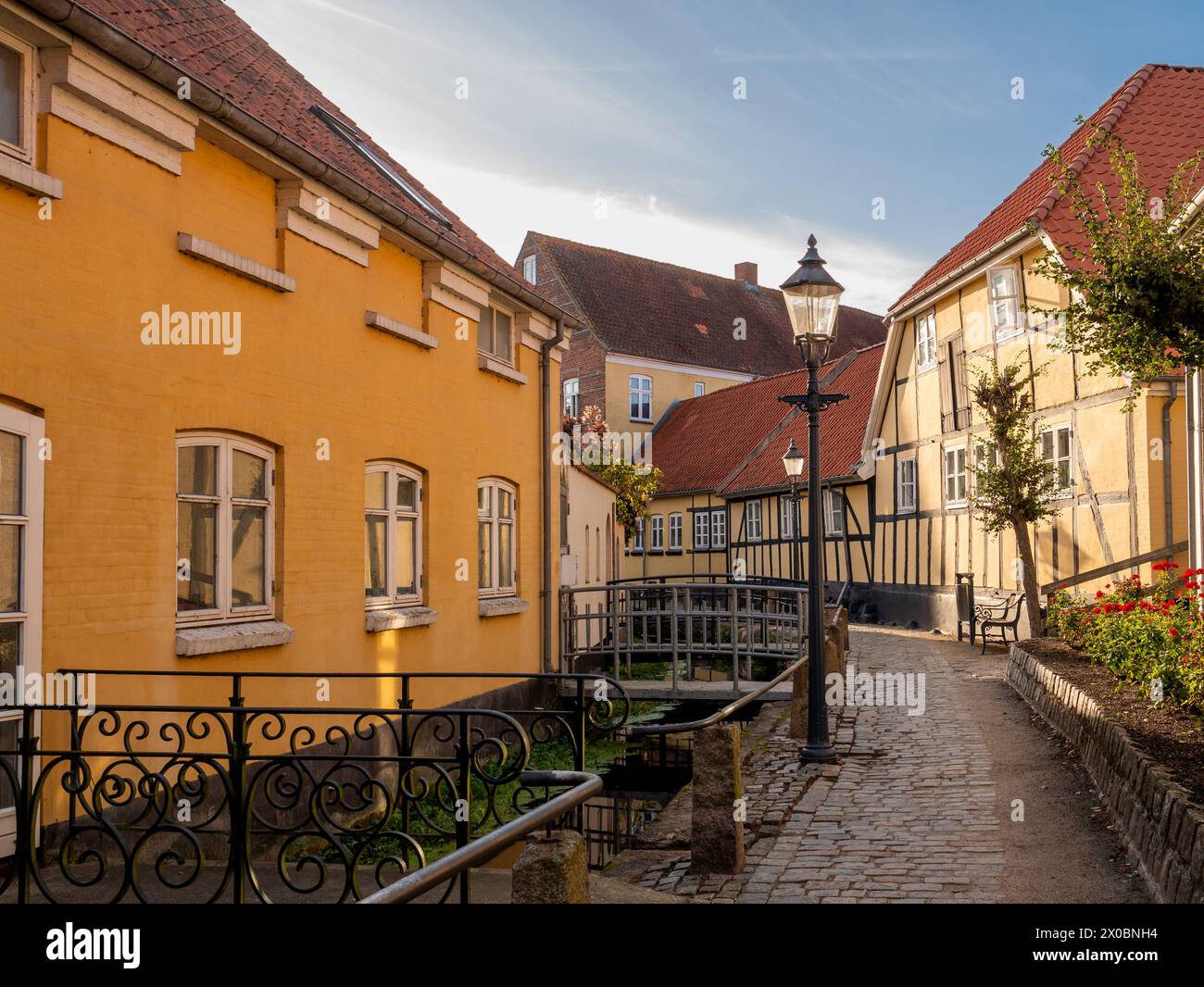 Affascinante strada stretta con case a graticcio lungo il canale nella città vecchia di Bogense, Funen, Danimarca Foto Stock