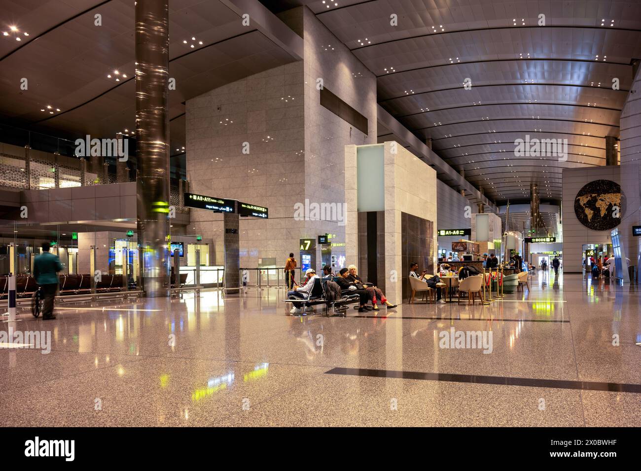 Terminal dell'aeroporto internazionale di Hamad con tutti i cancelli e i viaggiatori che passano. Foto Stock