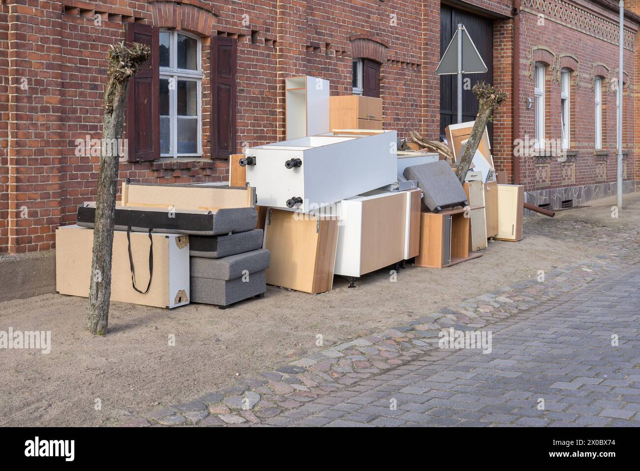 Pile di rifiuti ingombranti con mobili sul lato della strada di fronte a una casa Foto Stock