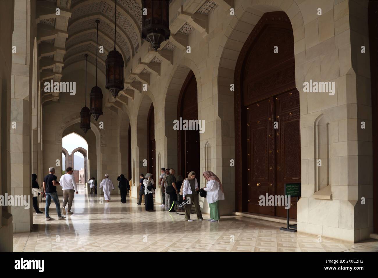 Visitatori della grande Moschea del Sultano Qaboos in Arcade (Riwaq) Muscat Oman Foto Stock Visitatori della grande Moschea del Sultano Qaboos in Arcade (Riwaq) Muscat Oman Foto Stock