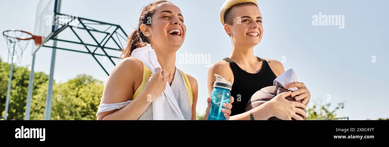 Due giovani donne con gli outfit atletici si trovano accanto a loro su un campo da basket, mostrando il loro lavoro di squadra e la loro amicizia. Foto Stock