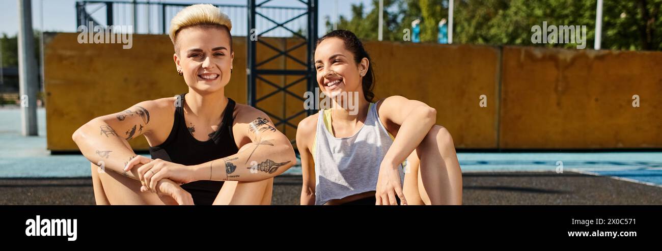 Due giovani donne sedute fianco a fianco, che si abbracciano dopo aver giocato a basket all'aperto in una giornata estiva di sole. Foto Stock