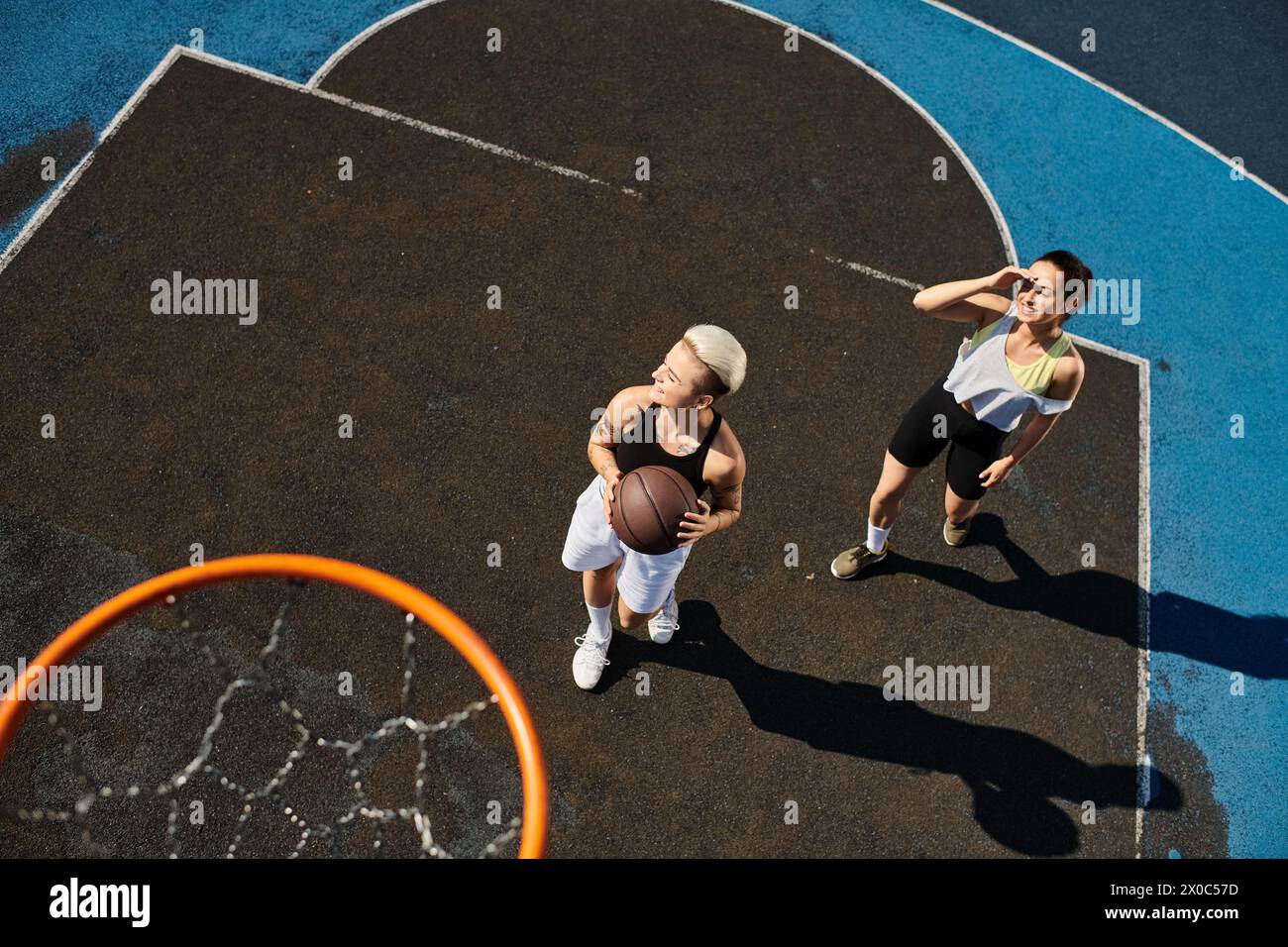 le donne giocano energicamente a basket su un campo, mostrando il loro atletismo e il loro lavoro di squadra sotto il sole estivo. Foto Stock