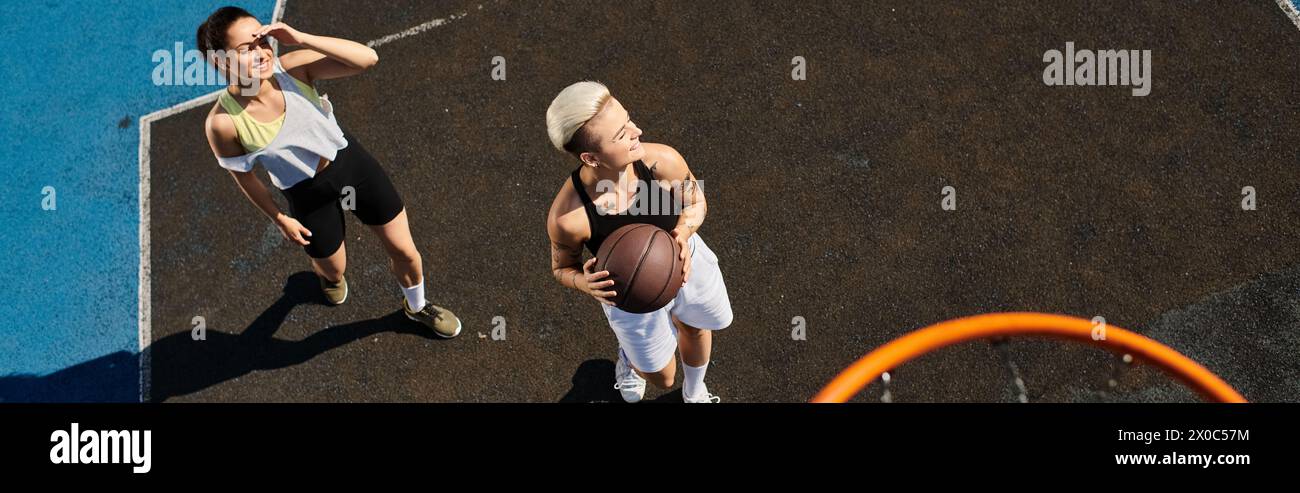 le donne giocano a un'intensa partita di basket su un campo all'aperto in una giornata di sole d'estate. Foto Stock