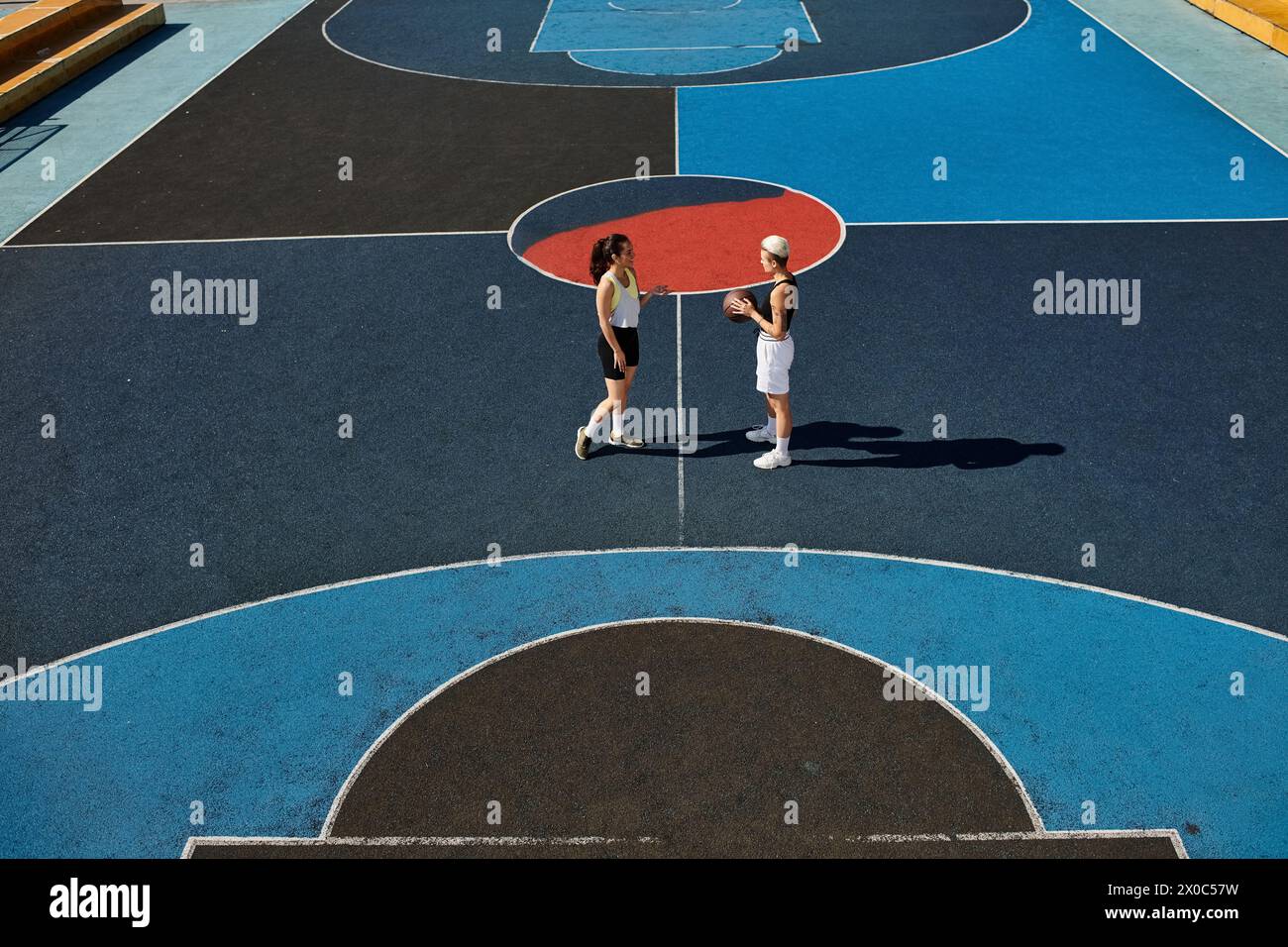 Le giovani donne giocano sapientemente a basket su un campo all'aperto, mostrando il loro atletismo e amicizia in estate. Foto Stock