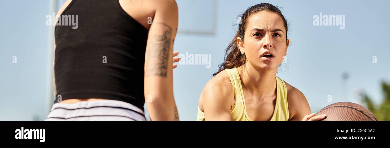 Una giovane donna, parte di un gruppo di amiche atletiche, tiene con sicurezza un basket all'aperto in estate. Foto Stock