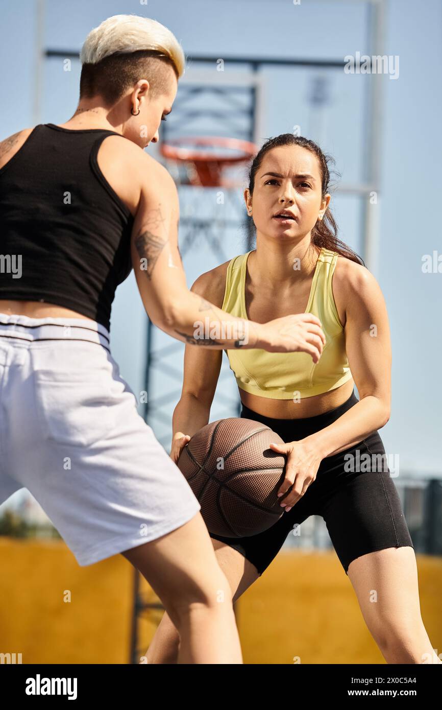 amici che giocano energicamente a basket su un campo all'aperto, mostrando il loro atletismo e la loro sportività. Foto Stock