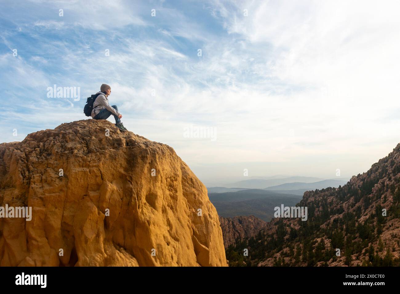 Donna che cammina seduto sulla cima di una montagna rocciosa che guarda il panorama Foto Stock
